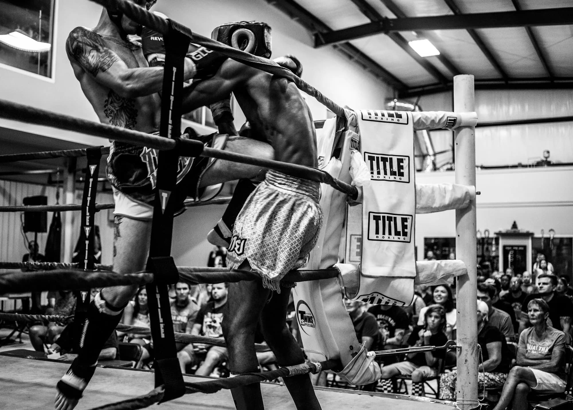Black and white photo of a fighter in the corner of a ring before a crowd